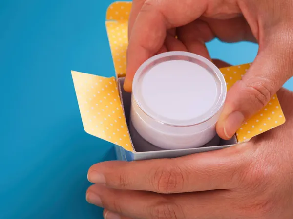 Una Mujer Sacando Crema Facial Una Caja Fondo Azul — Foto de Stock