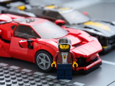 Tambov, Rusya Federasyonu - 09 Temmuz 2021 Lego pilotu minifiki Ferrari F8 Tributo ve Lego Chevrolet Corvette C8.R yarış arabalarının yanında duruyor. Lego Hız Şampiyonları.