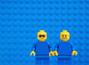 Tambov, Rusya Federasyonu - 17 Ekim 2021 Biri güneş gözlüklü, diğeri mavi arka planlı iki lego figürü. 