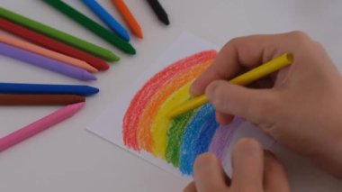 Sarı mum pastel boya ile gökkuşağını boyayan kadın..