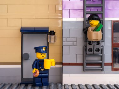 Tambov, Rusya Federasyonu - 5 Temmuz 2021 Lego polisi kahve içip çörek yerken soyguncunun biri köşedeki para dolu çantayla kaçmak için merdivene tırmandı.