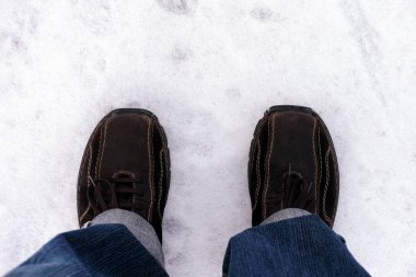 Kışlık ayakkabılar içinde kar üzerinde duran insan ayakları