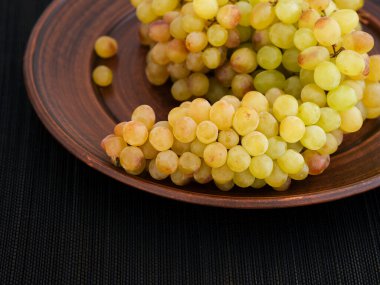 Tabakta bir demet gül üzümü. Siyah peçete arkaplanı 