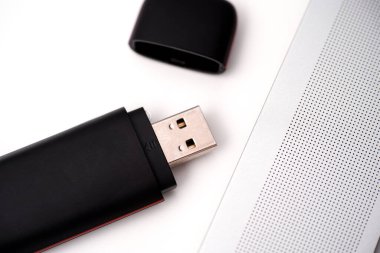 Masadaki bir dizüstü bilgisayarın yanındaki siyah USB USB bellek. Yakın plan.