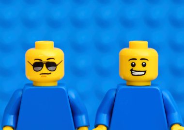 Tambov, Rusya Federasyonu - 17 Ekim 2021 - Biri güneş gözlüklü, diğeri mavi arka planda sırıtan iki Lego figürü. Yakın plan.