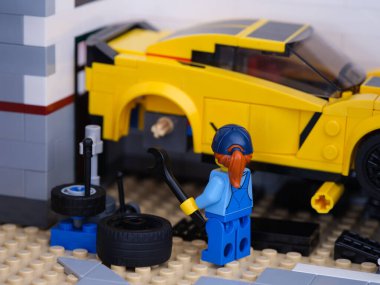 Tambov, Rusya Federasyonu - 3 Ocak 2022 Lego kız tamirci Lego Chevrolet Corvette 'in tekerleğini değiştiriyor