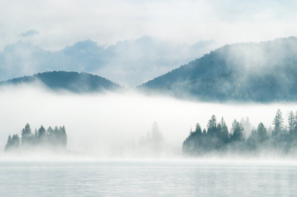 Heavy fog in the early morning on a mountain lake