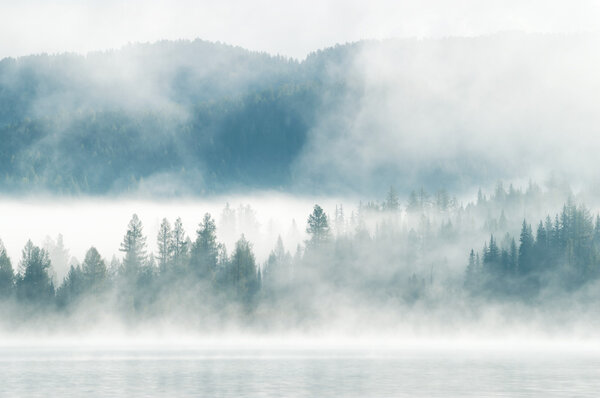 Heavy fog in the early morning on a mountain lake