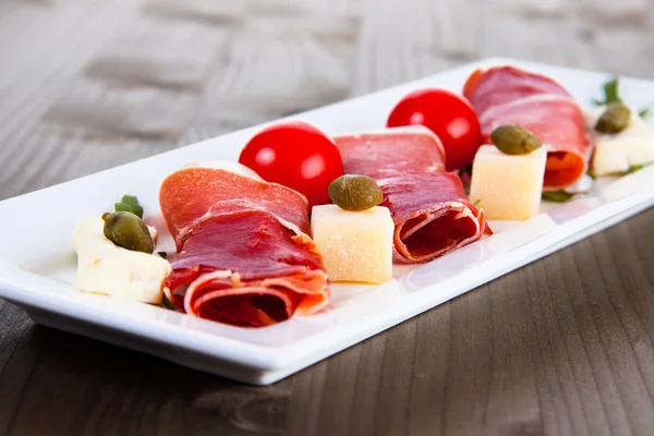 Slices of Delicious Prosciutto with capers, olives and cheese — Stock Photo, Image