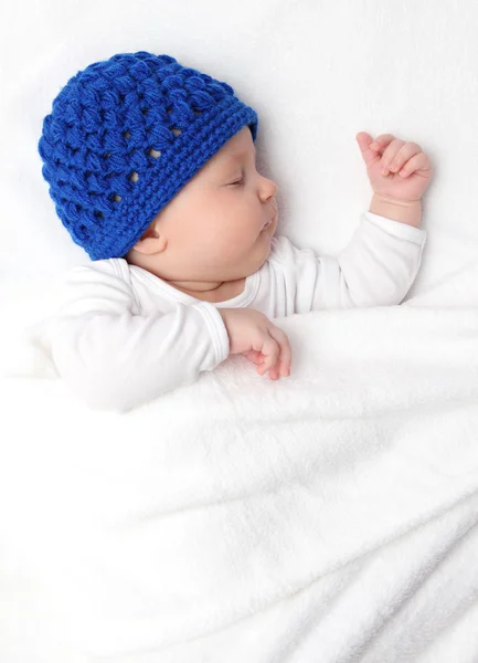 Beautiful baby sleeping on bed under a white blanket — Stock Photo, Image