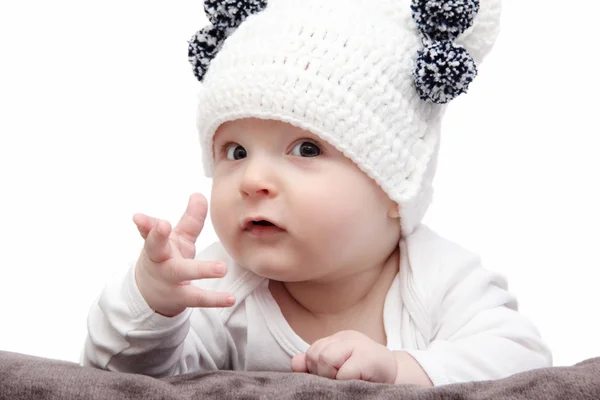 Baby in white hat lies on bed — Stock Photo, Image