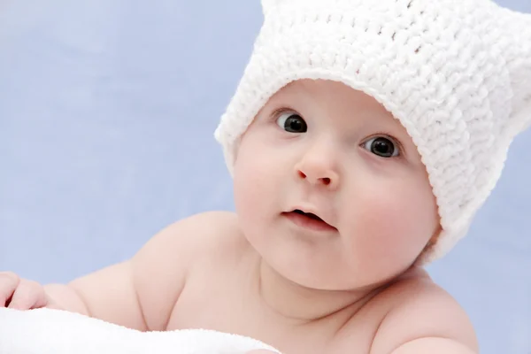 Bebê em chapéu branco jaz na cama — Fotografia de Stock