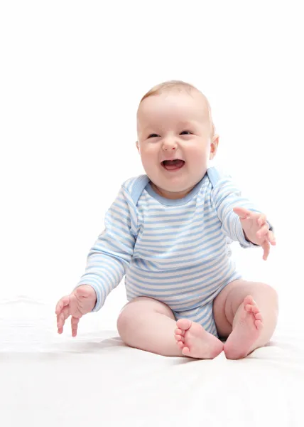 Mooie lachen gelukkig babyjongen zittend op witte bed Stockafbeelding