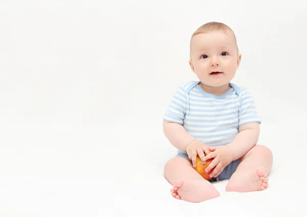 Bellissimo bambino felice seduto sul letto bianco con mela — Foto Stock