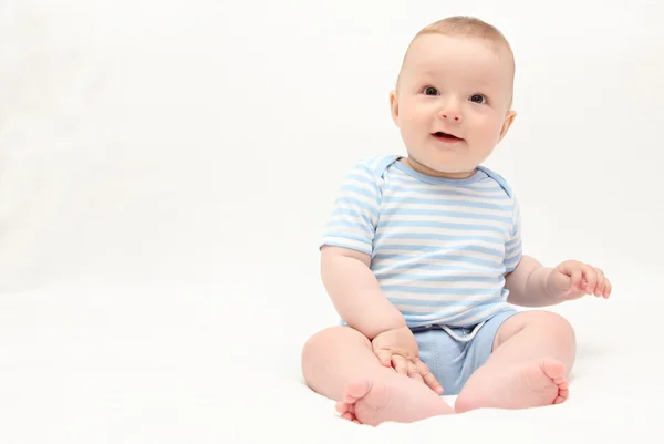 하얀 침대에 앉아 아름 다운 웃는 행복 한 아기 소년 로열티 프리 스톡 사진