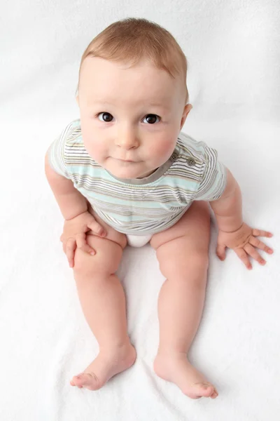 白いベッドに座って美しい笑う赤ちゃん — ストック写真