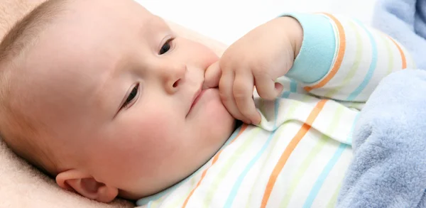 Baby in bed with finger in mouth — Stock Photo, Image