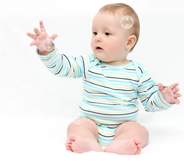 Baby spielt mit Seifenblasen Stockbild