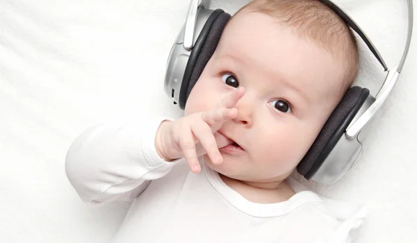 Babyjongen met hoofdtelefoon ligt op rug Stockfoto