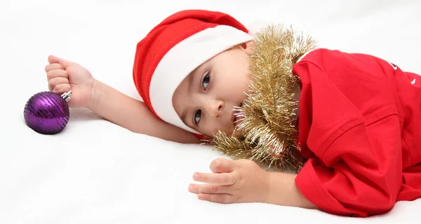 Kind mit Weihnachtsmann-Mütze liegt auf Bett — Stockfoto