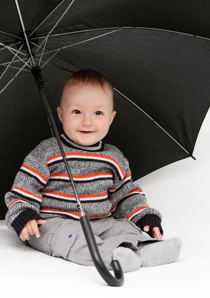 Junge sitzt unter Regenschirm — Stockfoto