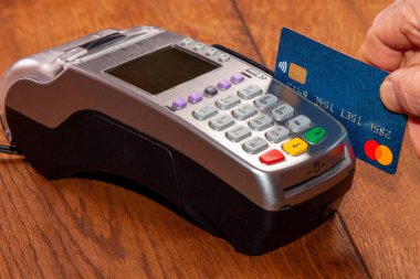    Bir el, POS terminalinde mal veya hizmetler için nakit ödeme için bir banka kartı tutar.