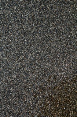 Deniz kıyısındaki siyah volkanik manyetik kum. Sahilin arka planında dalgalar birbirine yakın.. 