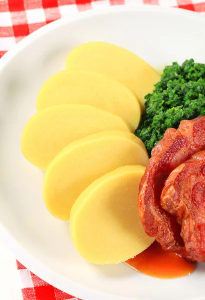 Gerookt varkensvlees nek met aardappel knoedels en spinazie — Stockfoto