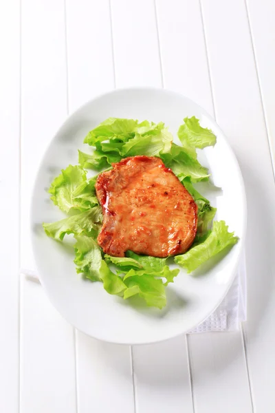 Glazed pork chop on lettuce leaves — Stock Photo, Image