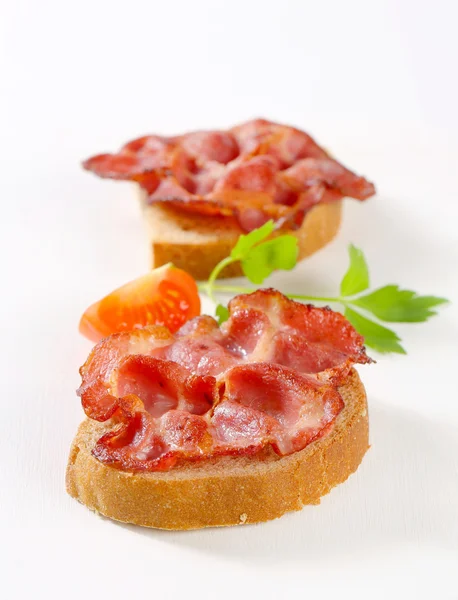 Krokante segmenten van varkensvlees op brood — Stockfoto