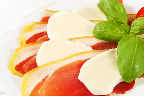 Prosciutto affettato e mozzarella con basilico e pomodori — Foto Stock