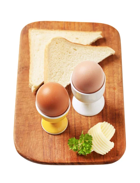Boiled eggs in eggcups and white bread — Stock Photo, Image