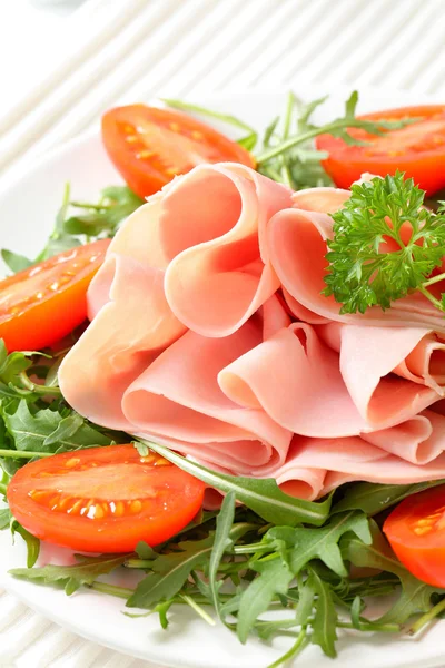 Sliced ham with arugula leaves and tomatoes — Stock Photo, Image