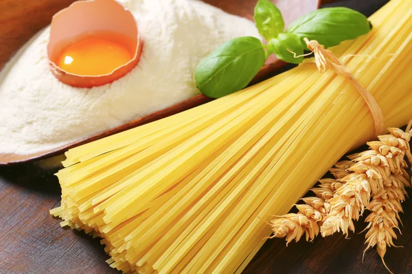 Dried spaghetti and scoop of flour with fresh egg — Stock Photo, Image