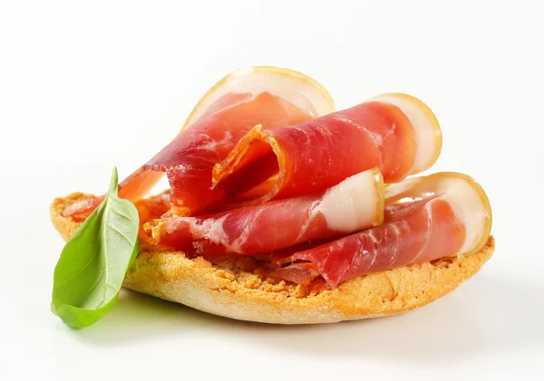Slices of prosciutto on crispy bread — Stock Photo, Image