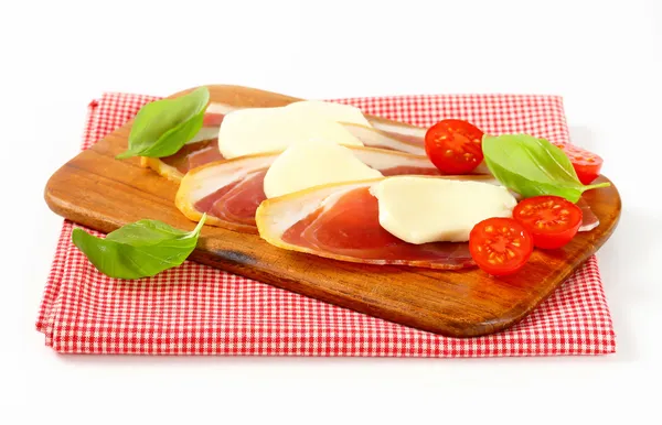 Sliced prosciutto and mozzarella with basil and tomatoes — Stock Photo, Image