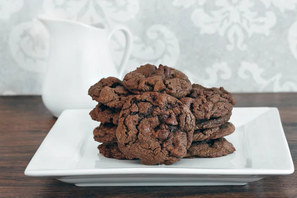 A stack of chocolate, chocolate chip cookies on a white plate. — Stock Photo, Image