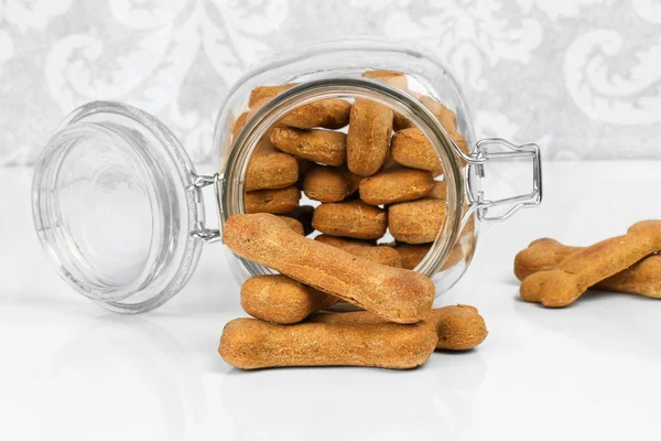 Homemade dog biscuits spilling from a glass canister. — Stock Photo, Image