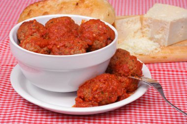 Bir kase kırmızı soslu İtalyan köftesi. Ekmek ve peynir arka planda. Makro