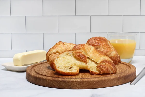 バターとオレンジジュースと丸いまな板の上にフレーク状のバターフランスのクロワッサン — ストック写真