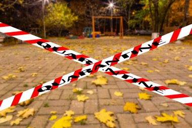 Moskova, Rusya 'da Coronavirus. Konut alanlarından birinde (bulanık manzara) bir sonbahar gecesinde boş bir oyun alanı. Karantina işareti. COVID salgını ve seyahat kavramı