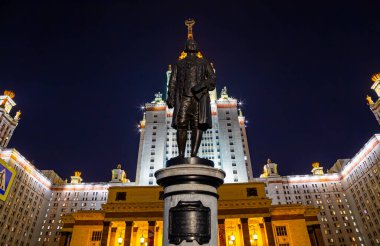 Rusya 'nın başkenti Sparrow Hills' teki Moskova Devlet Üniversitesi 'nin (MSU) ana binasının yanından Mikhail Vasilyevich Lomonosov anıtının (sonbahar akşamı) görüntüsü.  