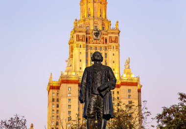 Rusya 'nın başkenti Sparrow Hills' teki Moskova Devlet Üniversitesi 'nin (MSU) ana binasının yanından Mikhail Vasilyevich Lomonosov anıtının (sonbahar akşamı) görüntüsü.  