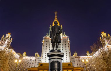 Rusya 'nın başkenti Sparrow Hills' teki Moskova Devlet Üniversitesi 'nin (MSU) ana binasının yanından Mikhail Vasilyevich Lomonosov anıtının (sonbahar akşamı) görüntüsü.  