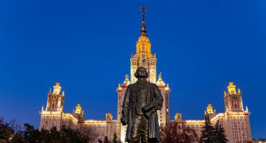 Rusya 'nın başkenti Sparrow Hills' teki Moskova Devlet Üniversitesi 'nin (MSU) ana binasının yanından Mikhail Vasilyevich Lomonosov anıtının (sonbahar akşamı) görüntüsü.  