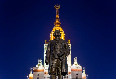Rusya 'nın başkenti Sparrow Hills' teki Moskova Devlet Üniversitesi 'nin (MSU) ana binasının yanından Mikhail Vasilyevich Lomonosov anıtının (sonbahar akşamı) görüntüsü.  
