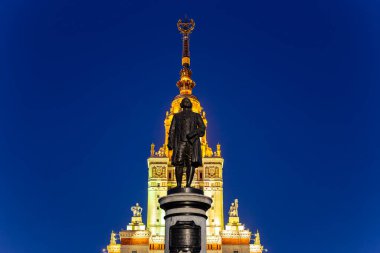 Rusya 'nın başkenti Sparrow Hills' teki Moskova Devlet Üniversitesi 'nin (MSU) ana binasının yanından Mikhail Vasilyevich Lomonosov anıtının (sonbahar akşamı) görüntüsü.  