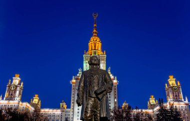 Rusya 'nın başkenti Sparrow Hills' teki Moskova Devlet Üniversitesi 'nin (MSU) ana binasının yanından Mikhail Vasilyevich Lomonosov anıtının (sonbahar akşamı) görüntüsü.  