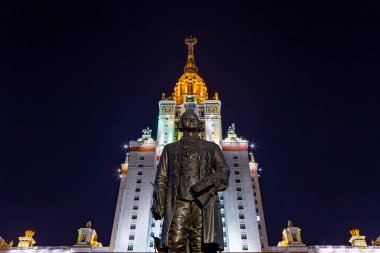 Rusya 'nın başkenti Sparrow Hills' teki Moskova Devlet Üniversitesi 'nin (MSU) ana binasının yanından Mikhail Vasilyevich Lomonosov anıtının (sonbahar akşamı) görüntüsü.  