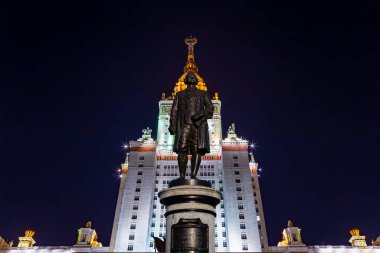 Rusya 'nın başkenti Sparrow Hills' teki Moskova Devlet Üniversitesi 'nin (MSU) ana binasının yanından Mikhail Vasilyevich Lomonosov anıtının (sonbahar akşamı) görüntüsü.  